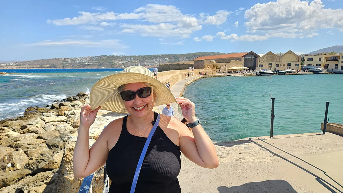 Mulher sorridente com chapéu na praia.