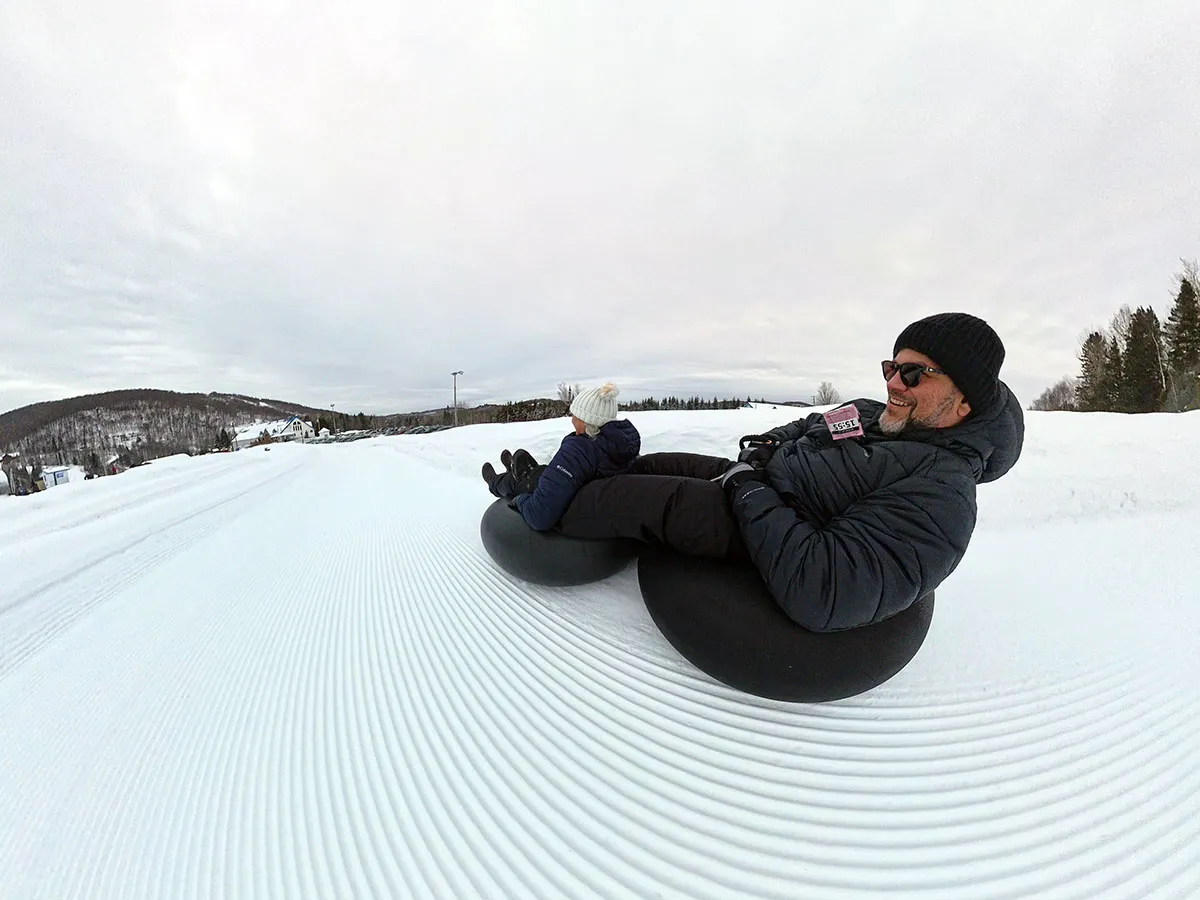 Homem deslizando em tubo na neve.