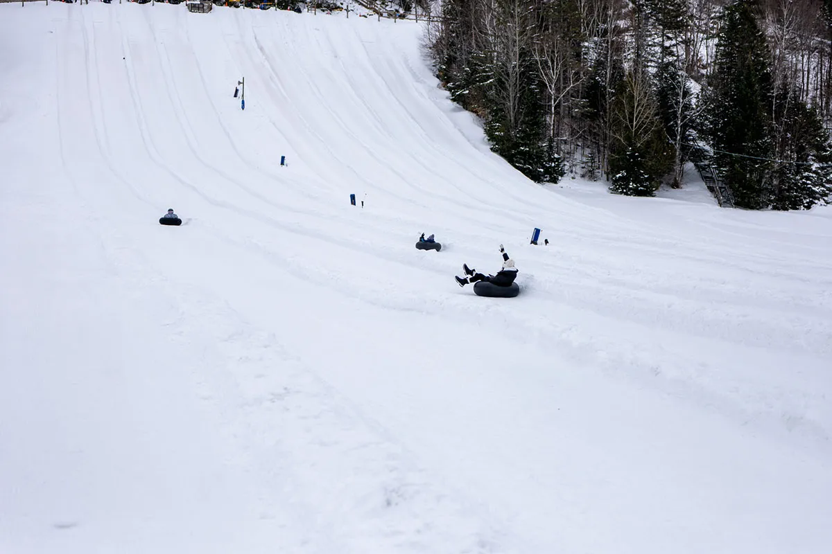Pessoas descendo em tubos na neve.