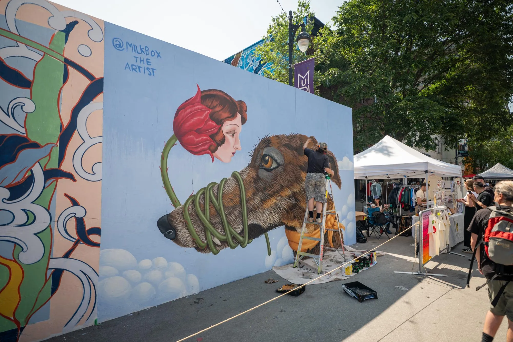 Artista pintando um grande mural colorido em prédio do Boulevard Saint-Laurent durante o Festival MURAL em Montreal