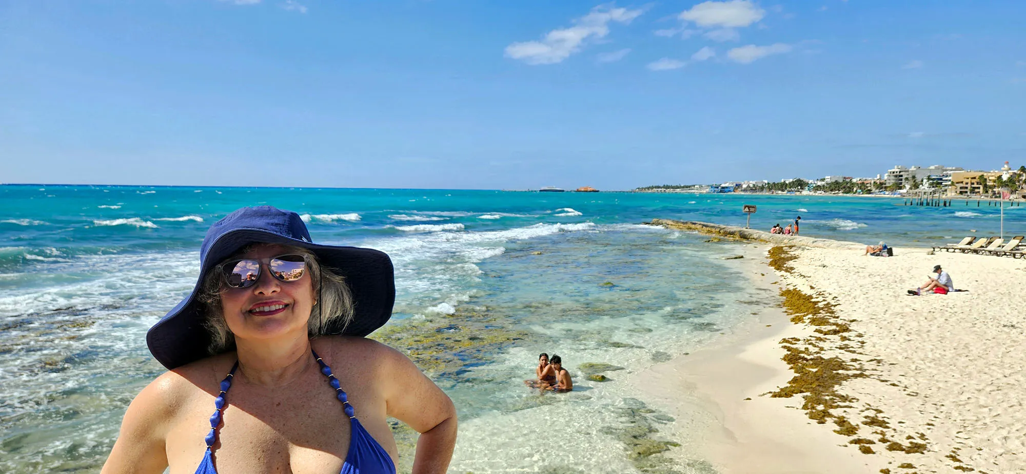 Vista da praia com sargaço acumulado na água sob céu nublado no México