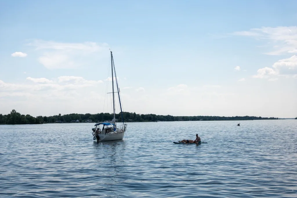 Veleiro flutuando e pessoa em stand-up paddle no Lago Saint-François